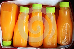 Close up Squeezed orange juice packed in clear plastic bottles