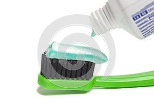 Close up of squeezing toothpaste on toothbrush on white background.