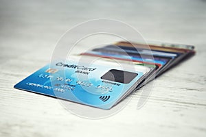 Close up of a stack of credit cards lying in order on the white table top. Many different credit cards with biometric card on top