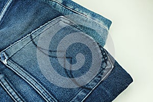 Close up of stack of jeans or denim pants isolated on white background.