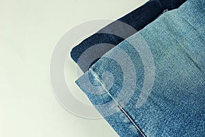 Close up of stack of jeans or denim pants isolated on white background.