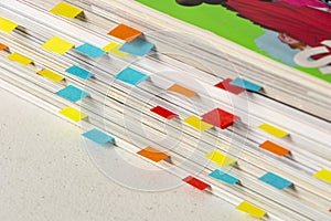 Close-up of stack of magazines with colored labels as bookmarks made with small colored papers