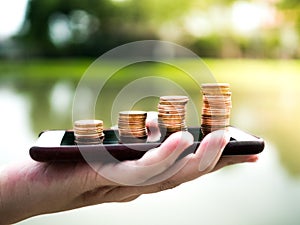 Close up stack of money coins on the mobile phone, business in eCommerce concept