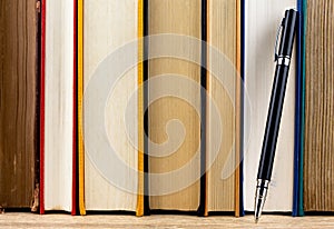 Close up stack of old books vertically placed on the wooden shelf