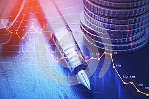 Close up of stacked coins, pen and forex chart on blurry desktop background. Financial management, money and accounting concept.