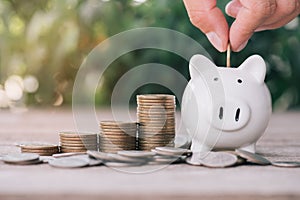 Close up of stacking gold dollars coins with Hand putting coin on PiggyBank ,Business Finance and Money concept,Save money for