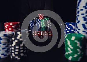 Close up stacks of different colored poker chips and playing dices on the casino table. Gambling tournament betting for success