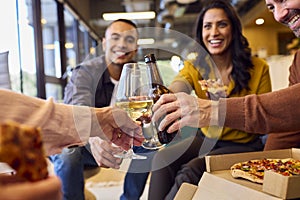 Close Up Of Staff At Informal Meeting In Office With Takeaway Pizza And Drinks