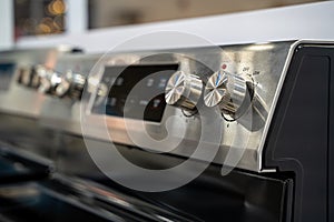 Close up of stainless steel stove control knobs and panel