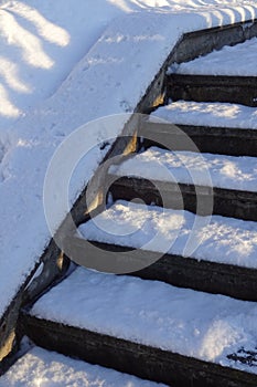 Close up of stair steps covered with fresh snow on a sunny day in park. January 2022