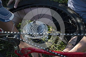 Close up, the star of the chain of switching speeds of a mountain bike and a removed wheel in the hand of a person, a cyclist