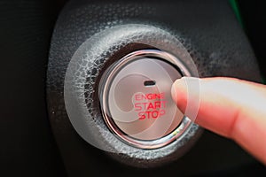 Close up start/stop engine button and finger pressing on a car