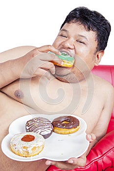 Close up of starving fat man eat donuts on studio