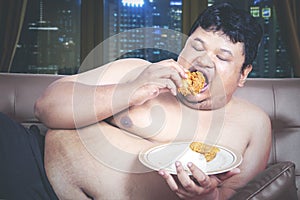 Close up of starving fat man eating fried chicken photo