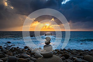 Nature Seascape with Zen Stacked Rocks on Beach in Little Sunshine at Sunrise photo