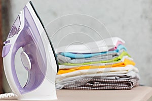 Close up steam iron colorful clothes washed laundry on white background. Housekeeping. Copy space advertisement. Place for text.