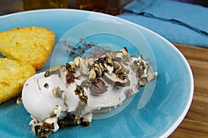 Close up of steamed chicken breast with thyme herbs, champignon mushrooms and fried grated potatoes rÃ¶sti on blue china dish