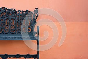 Close up of steel bench against a orange wall.