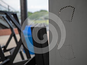 Close up steel, cutout payphone symbol in a messy, unmanaged area