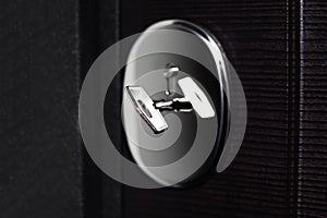 Close-up of steel key in lock of modern apartment house. Black background.