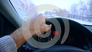 Close-up of steering wheel with hands on it during car driving. Winter road driving.