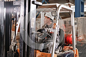 Close - up steering wheel and levers. man driving a forklift through a warehouse in a factory. driver in uniform and
