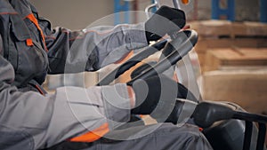 Close - up steering wheel and levers. man driving a forklift through a warehouse in a factory. driver in uniform and