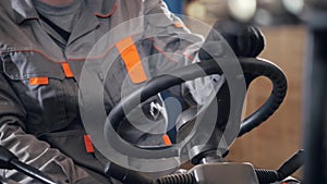 Close - up steering wheel and levers. man driving a forklift through a warehouse in a factory. driver in uniform and