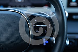 Close up of steering wheel of a new electric vehicle. Electric car control devices. Cruise control buttons, speed