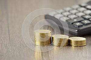 Close up step gold coins have blur calculator wood background