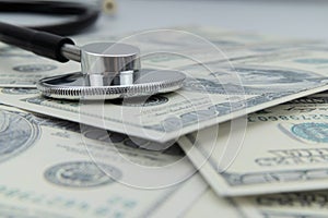 Close-up of a stethoscope on dollar bills, heap of dollars
