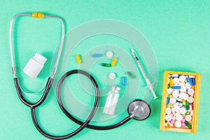 Close-up stethoscope and yellow apple on light green background with pills in wooden box. Top views