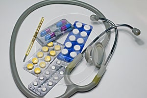 Close up of stetoscope,thermometer, tablets and capsules