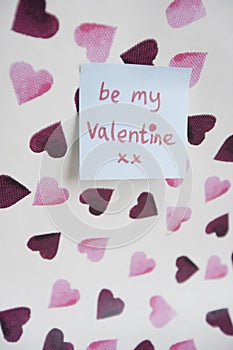 Close-up of sticky note with a orthographic message over heart shaped background