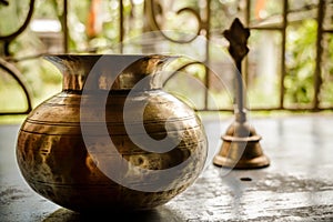 Close up Still Life of antique Holi water pot and bell on rustic floor. Faith, Tradition, Spirituality, Prayer, symbols of peace