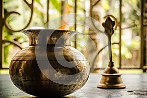 Close up Still Life of antique Holi water pot and bell on rustic floor. Faith, Tradition, Spirituality, Prayer, symbols of peace