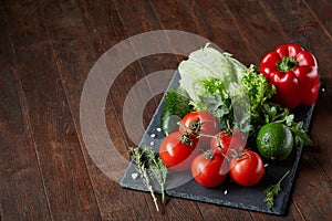 Close-up still life of assorted fresh vegetables and herbs on wooden rustic background, top view, selective focus.