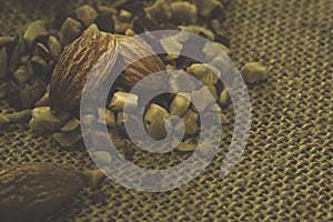 close up still life photo of almond seeds on grounded almonds for sprinkling sweet food on the hemp sack sheet