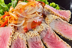 Close Up Still Life of Roasted Tuna Steaks Crusted with Herbs and Sesame Seeds on Dark Gray Surface