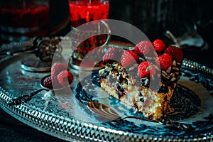 Close up still life in royal style. Close up piece of chocolate cake with raspberries on old blue plate, beside glass fruit drink