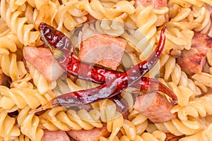Close-up stir-fried fusilli pasta with sliced bacon, garlic and