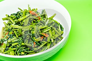Close up of stir fried water spinach on a white bowl