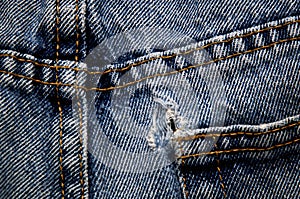 Close up of stitching and hole in old denim blue jeans