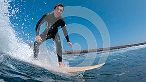 CLOSE UP: Stoked surfboarder smiling and riding a wave to the coast in Spain.