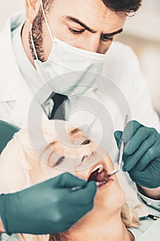 Close up of stomatologis checking teeth of elderly lady