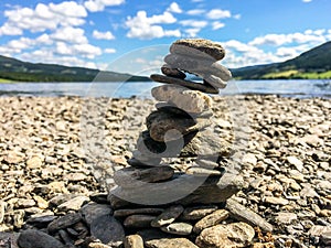 Close-up of stone cairn on a pebble beach with mountains and lake in the background