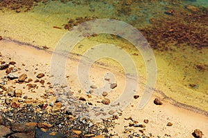 Close up of stones and clear water on the shore of a beach