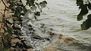 Close-up of a stony beach at evening, small waves of the river, slow motion shot.