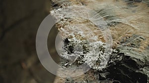 Close-up of a stony beach at evening, small waves of the river, slow motion shot.