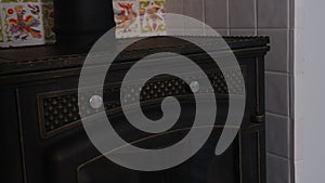 Close up of stove firewood heater inside apartment with white small tiles with animals and flowers behind. Creative. Old